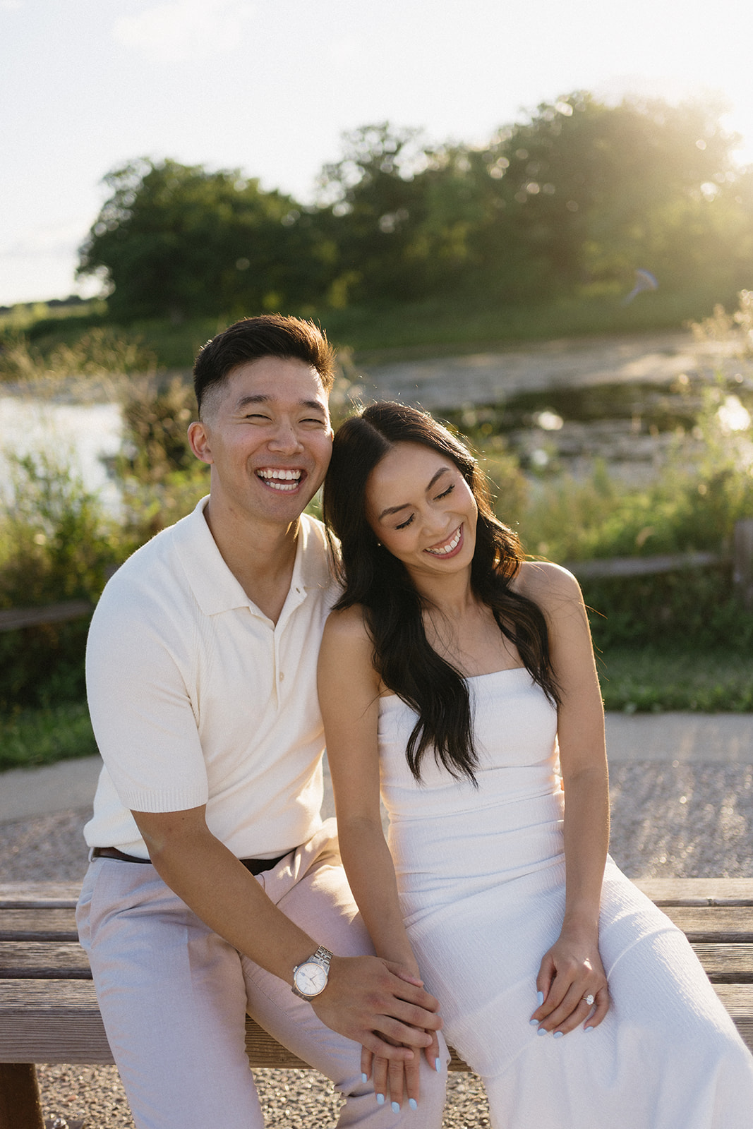 Chicago North Shore engagement session at Lake Forest lakefront preserve with couple sitting together laughing by Lake Michigan