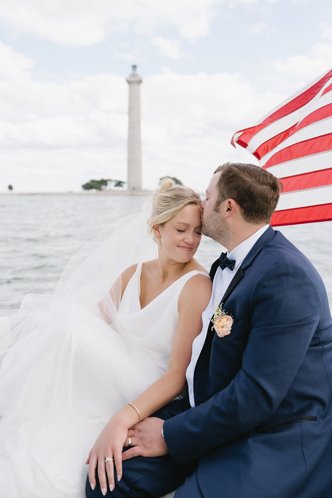 Bride and groom on a boat during their Put-in-Bay island wedding as the groom kisses the bride's forehead on Lake Erie